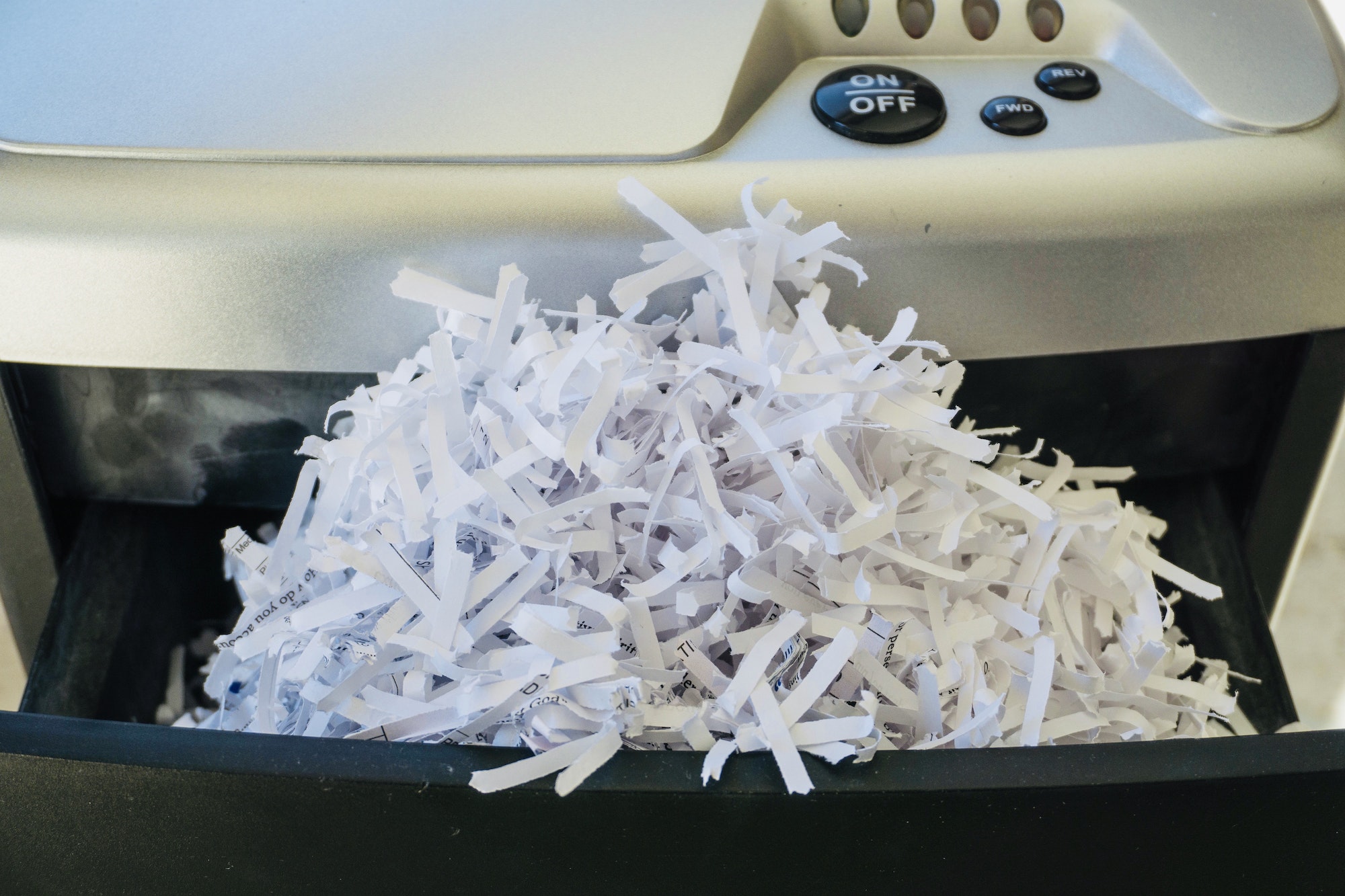 Shredded paper bulging out of a paper shredder Shredding day